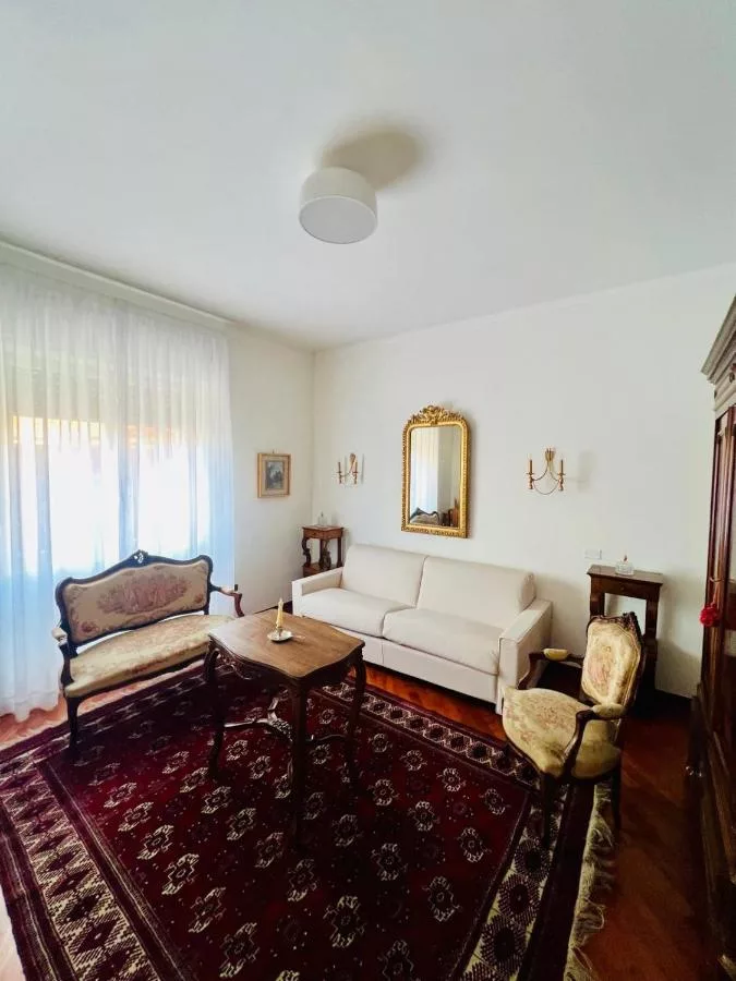 Salotto con specchiera dorata, tappeto persiano e parquet